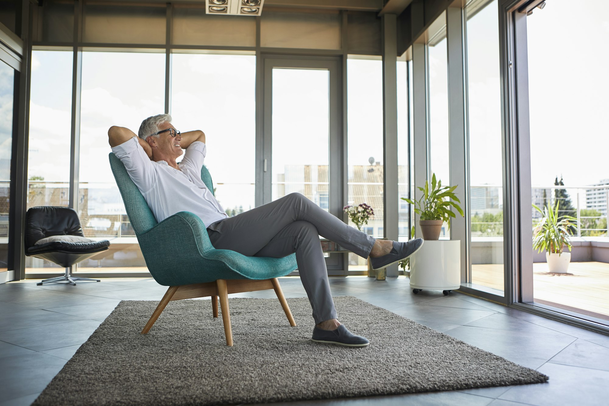 Smiling mature man relaxing in armchair at the window at home